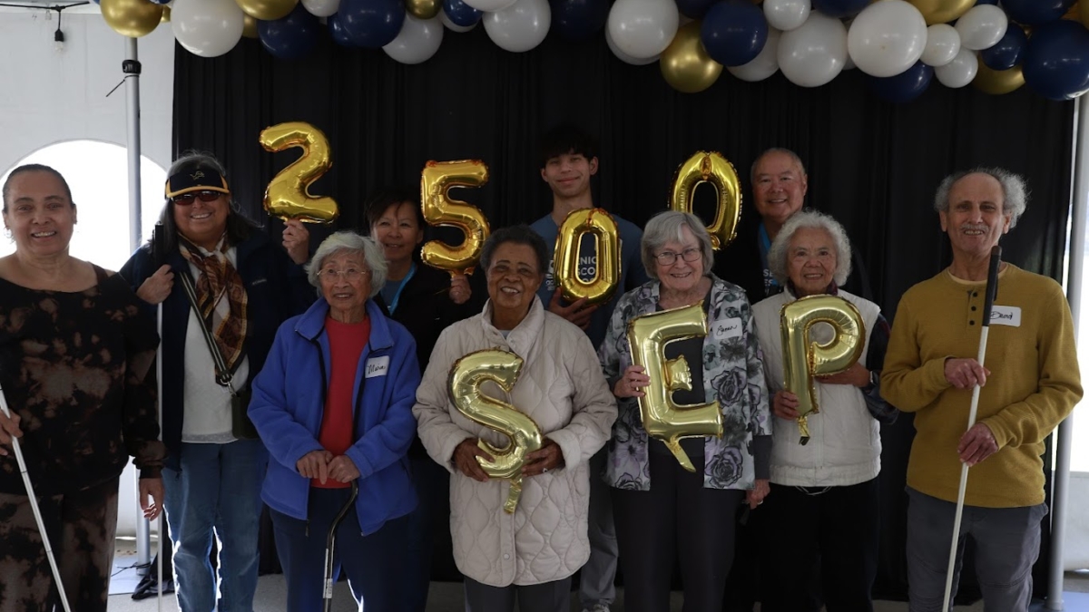 group of walker participants and volunteers holding gold balloons spelling out 2500 SEP
