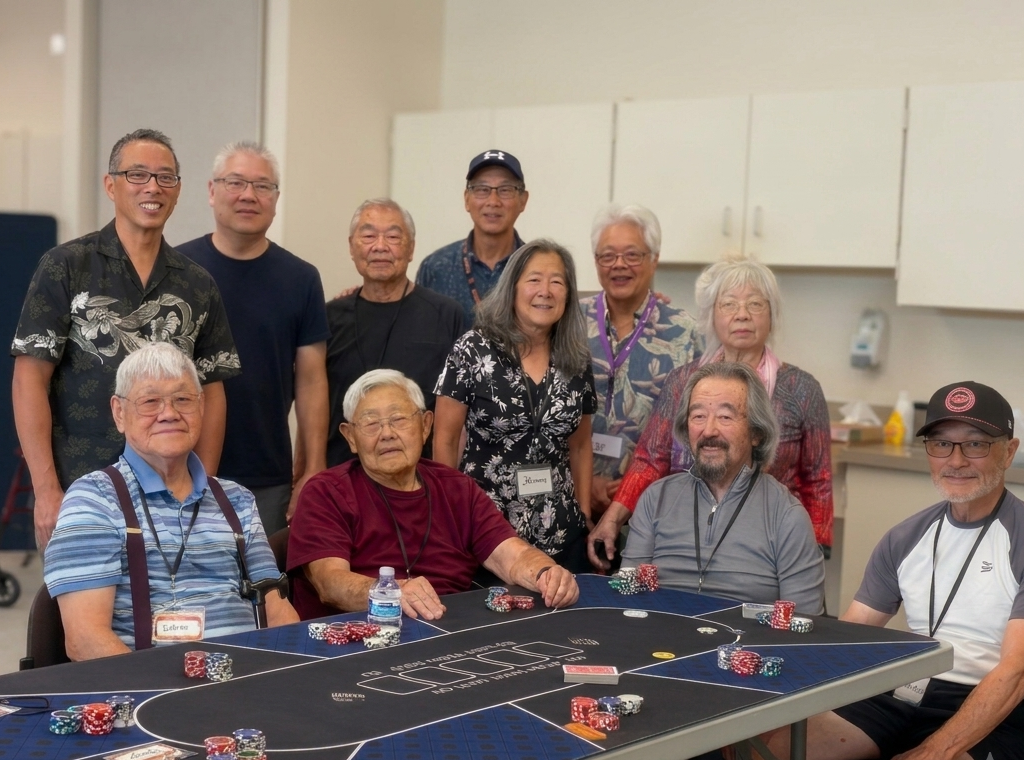 Eleven older adults pose and smile around a blue poker table with chips and cards. Some are seated, others stand behind, in a bright room with white cabinets.